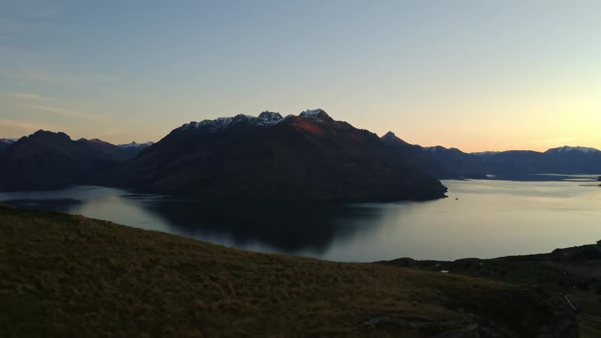 The sun is setting in the horizon of a reflective lake