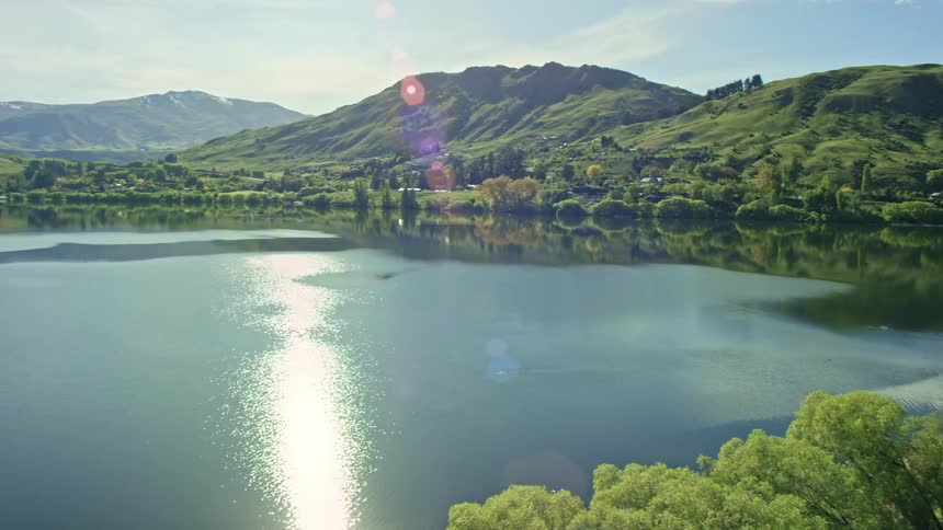 Calm surface of a lake surrounded by lush vegetation in the middle of the mountains at daytime