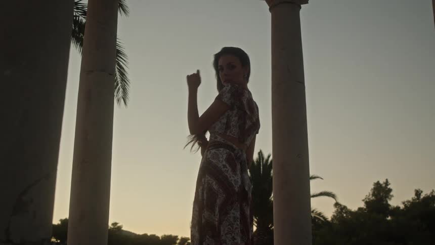 A woman lifts the bottom of her skirt and turns around while posing