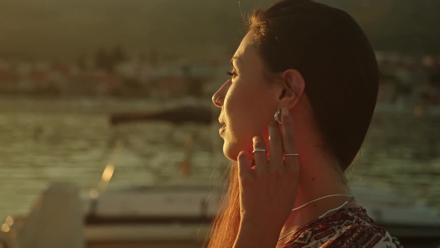 A woman is outdoors and watching the sun set