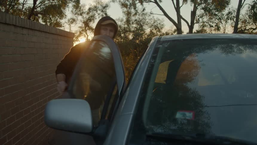 Man with black hoodie backpack and jeans breaks into car using poker