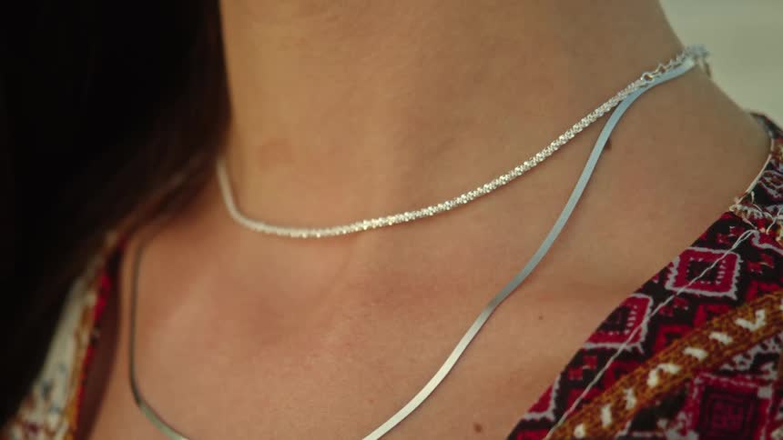 A woman showing off necklaces and rings