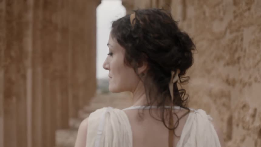 A woman is looking to her left near some pillars