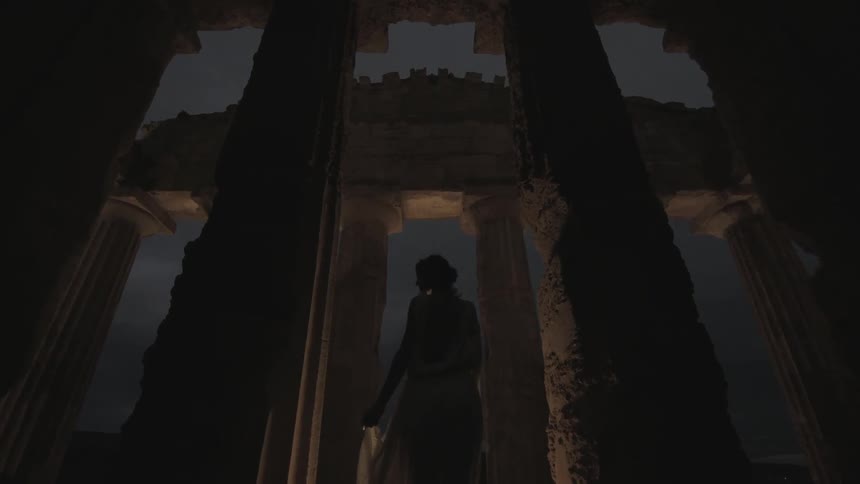 A person is standing in the dark under pillars
