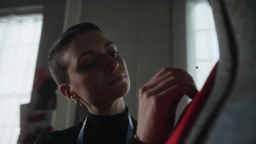 Young female couturier tailoring a suit over a mannequin on her studio