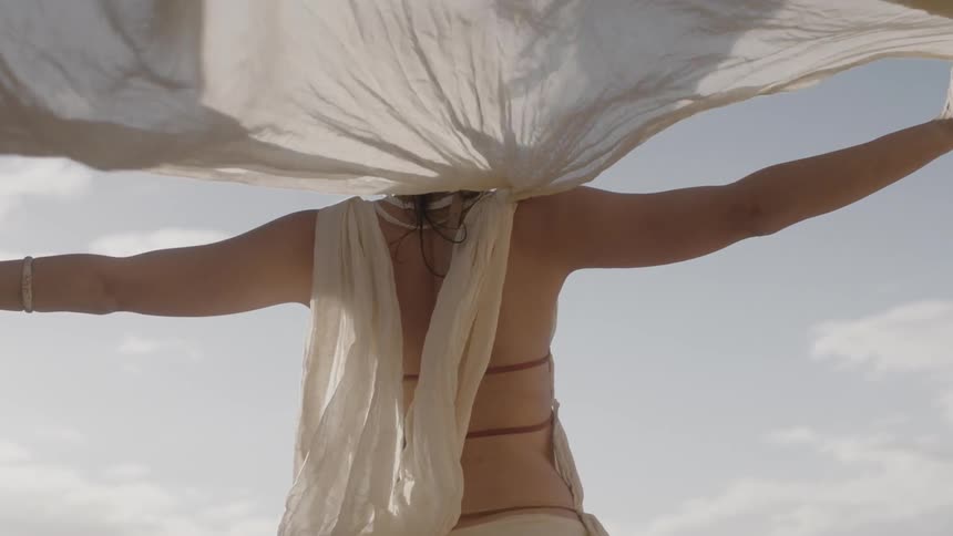 A woman holds her white robe in the wind