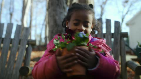 A child carries flower pots in the yard