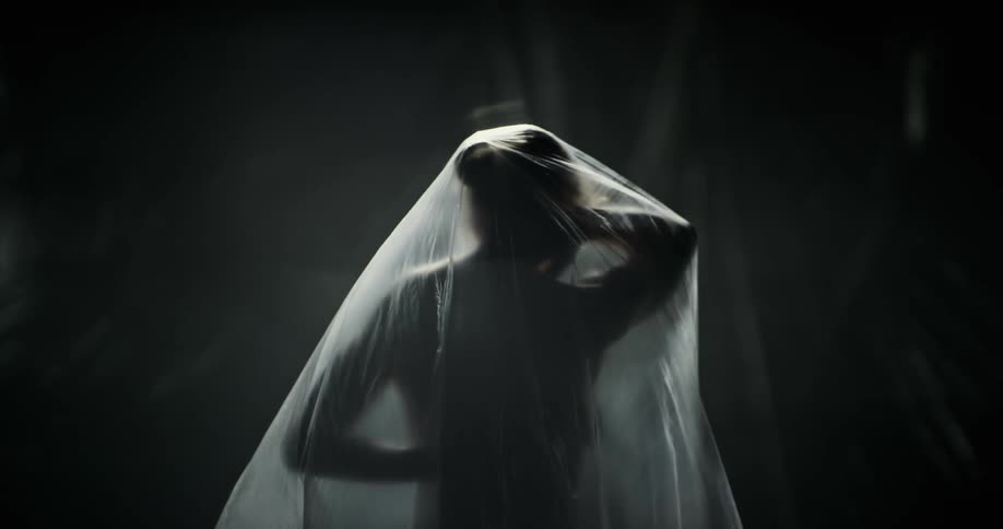 A woman covered in plastic moves her arms around