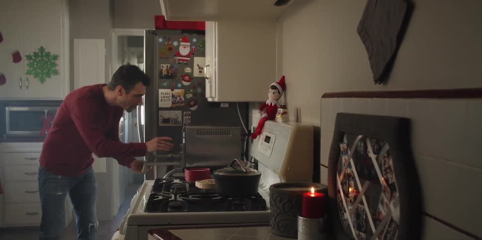 A man at home places a tray of cookies in an oven and carefully sets the timer