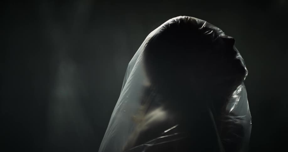 A person struggles under the plastic sheet