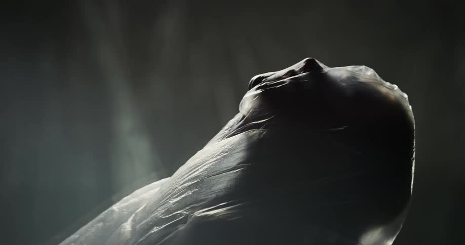Female performer draped in plastic moves through poses