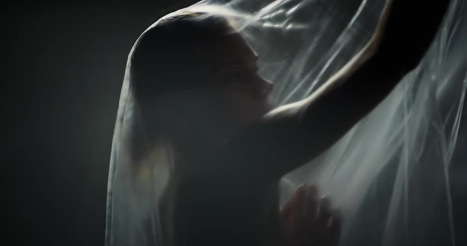 A woman is moving around under the plastic sheet