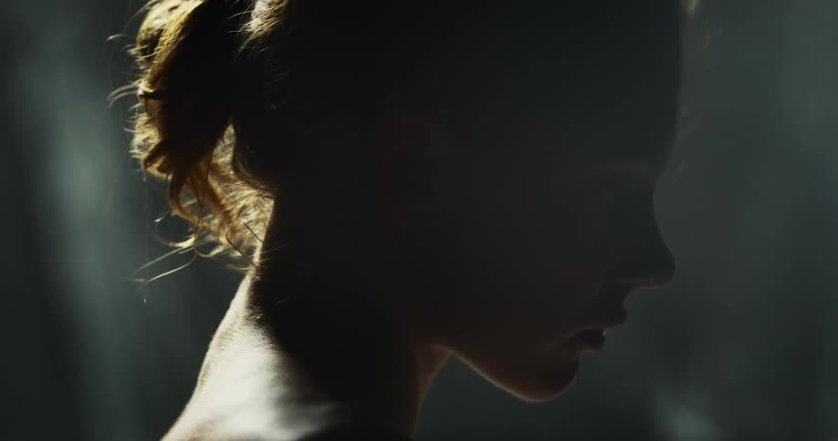 Side profile of topless woman with brown ponytail