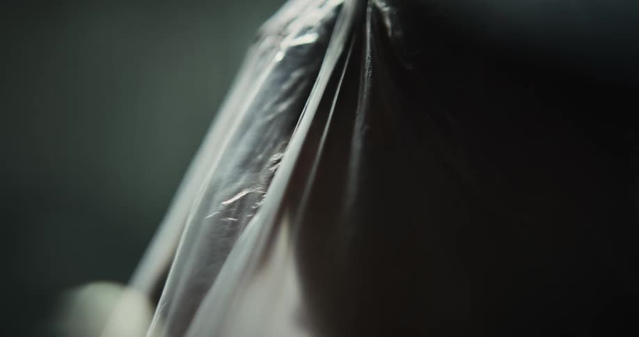 A woman is covered with a sheer veil and she moves her hands under the fabric