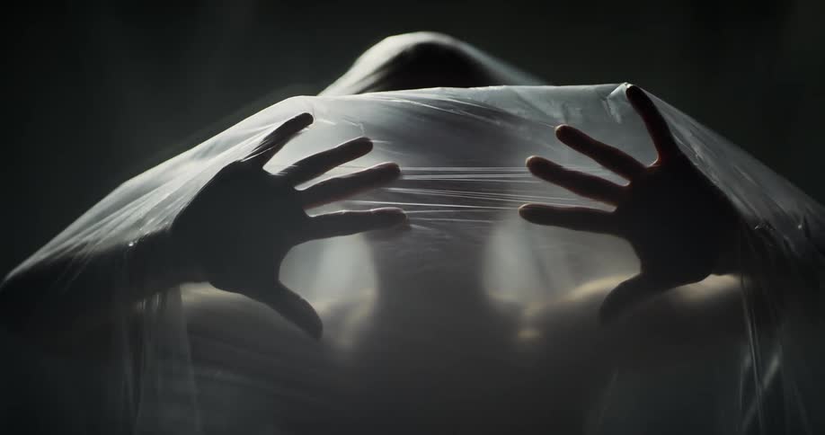 A woman wearing a veil slowly puts her hands out as if she is pushing something away