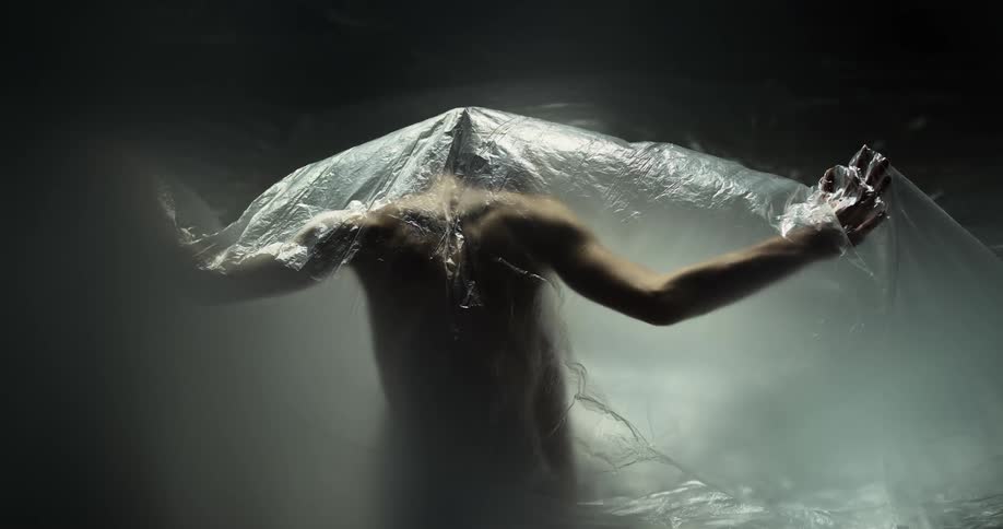 The muscles of female performers back can be seen as she performs under a sheet of plastic