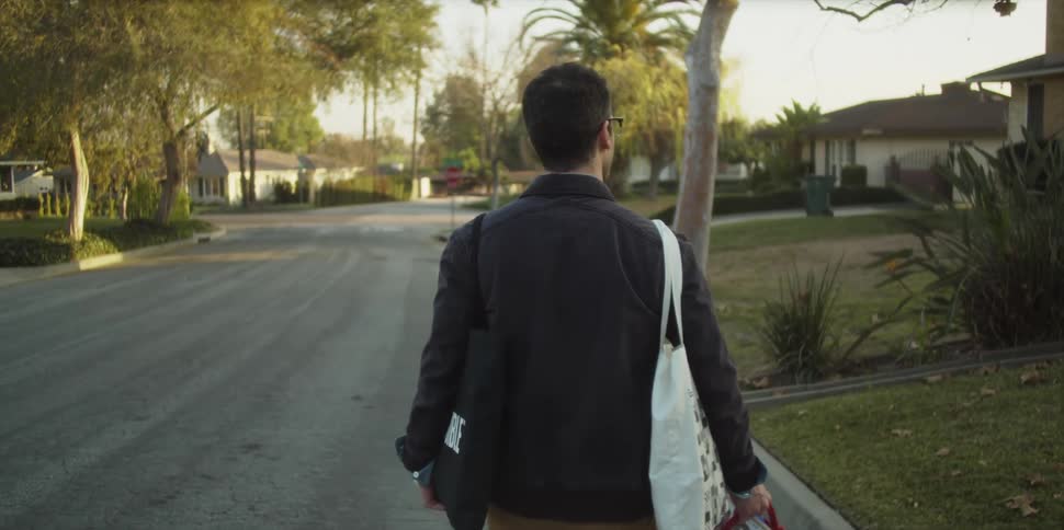 A man is walking down the street holding bags