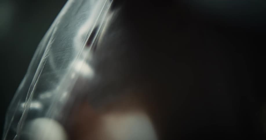 A woman is moving under the plastic sheet in the dark