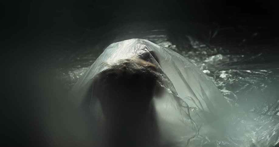 A person slowly moves under the plastic sheet