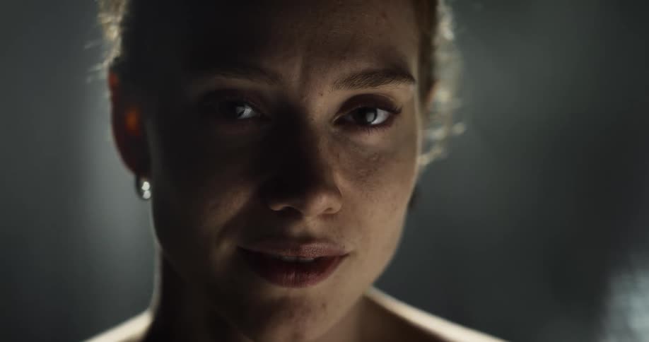 Young attractive woman on a dimly lit room turns around to look at the camera