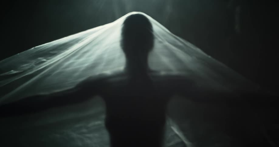 A person reaches up under the plastic sheet