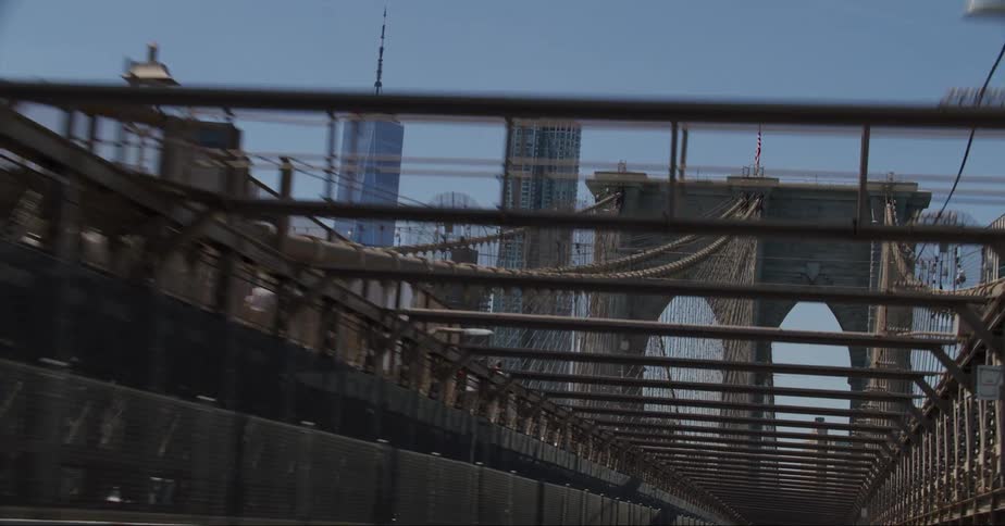 Traveling across the brooklyn bridge past pedestrians toward the city skyline