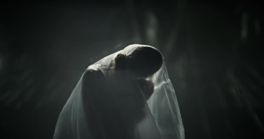 Plastic sheet covered back of female performer is seen as she moves through poses