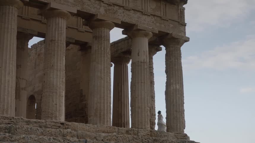 Woman standing between pillars of ancient building