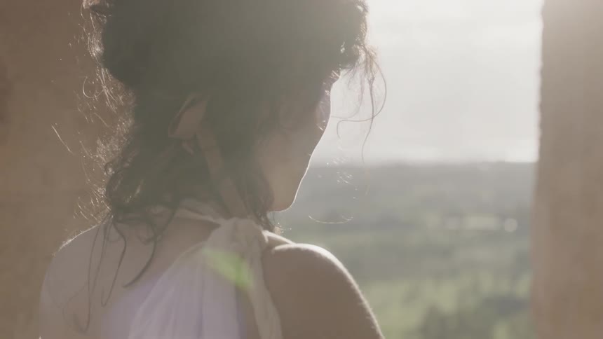 A woman looks over some green fields ahead