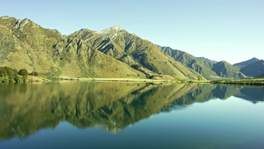 The mountains are reflected on the smooth surface of moke lake in new zealand