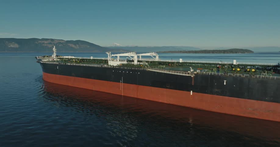 Aerial view of an oil tanker sailing on calm waters near a coastal mountain range