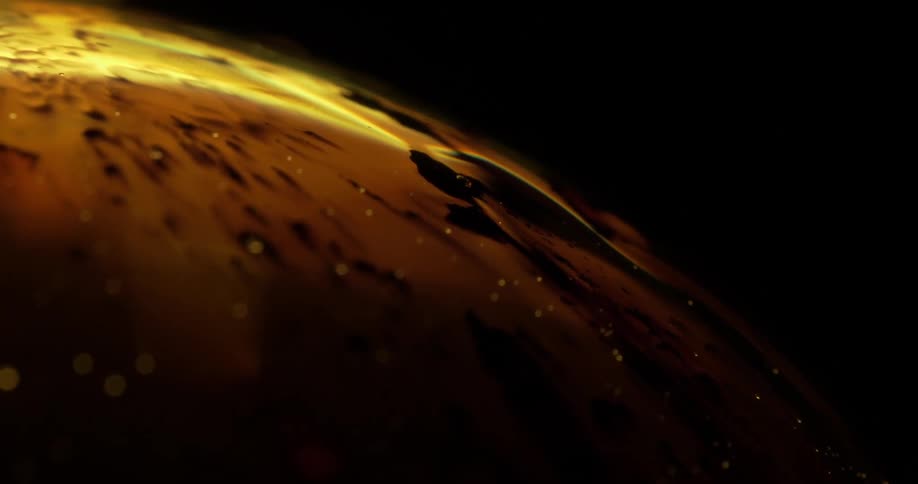 Light shines on small yellow spheres as they move around a round yellow object in the darkness