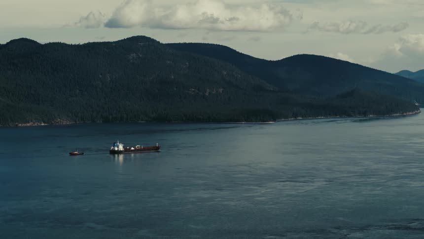 Aerial view of an oil tanker sailing on calm waters near a coastal mountain range