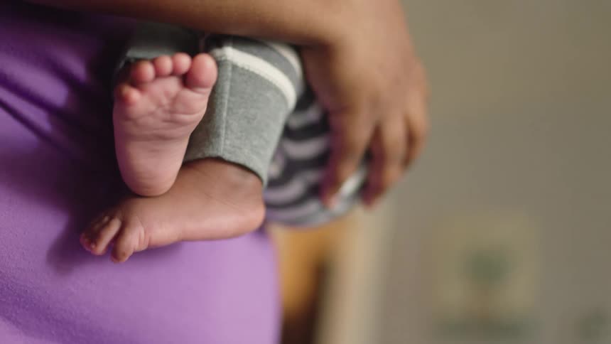 Mother holds child in her arms and gently rocks him while standing