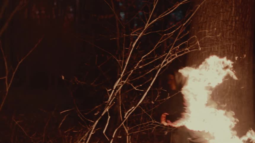 Man runs through woods at night as fire burns his clothes