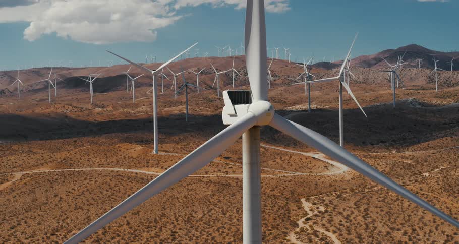 Wind turbines spin on a wind farm in a hilly countryside during the day