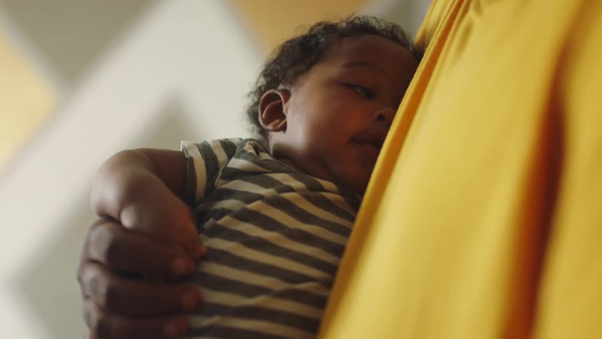 Loving father wearing a yellow shirt holding a toddler close to his chest