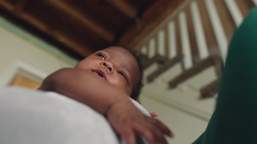 A baby smiles while resting on a couch cushion