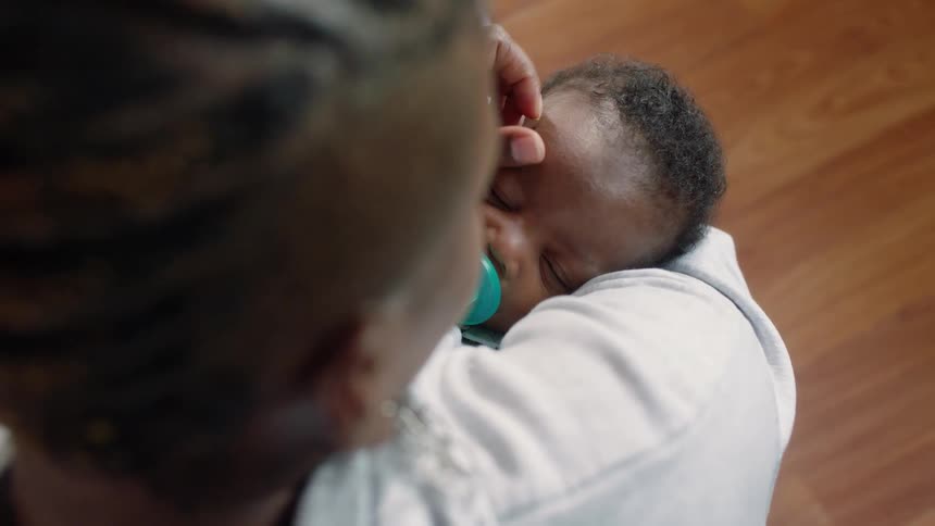 A woman cleans her babys eyes and kisses its forehead