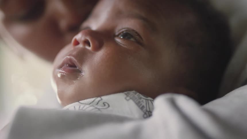A mother holding her baby reaches down and kisses him