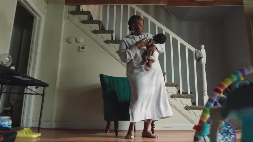 A mother carries her baby into the living room
