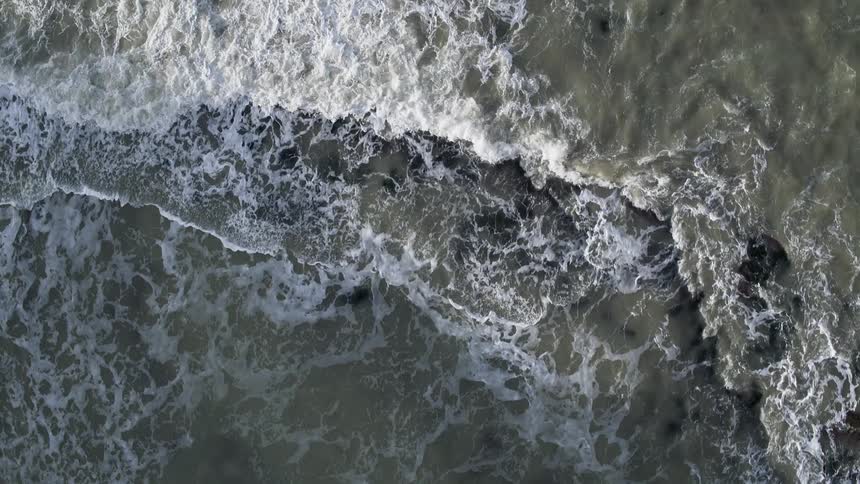 Waves crash against the rocks below