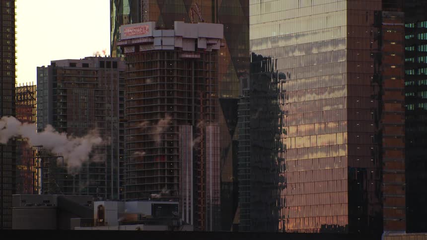 Smoke floats across city toward skyscraper reflecting red sky