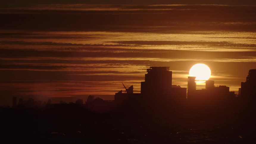 Sun on a red sky setting behind the silhouette of the city skyline