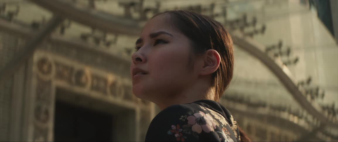 A woman looks over her shoulder at her surroundings while standing outdoors during the day