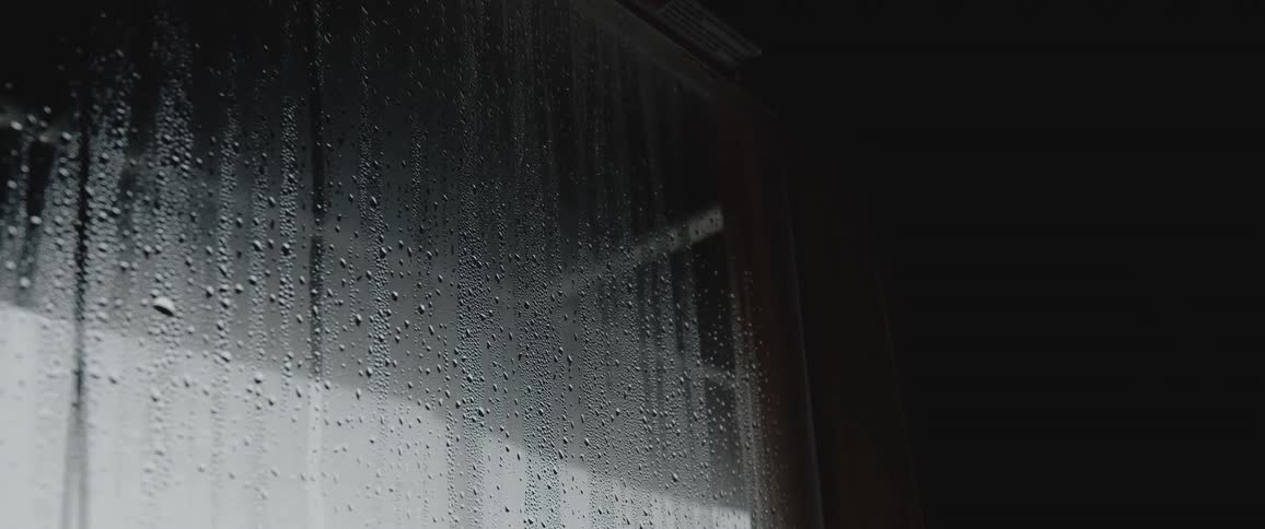Condensation covers glass of window sitting under overhang