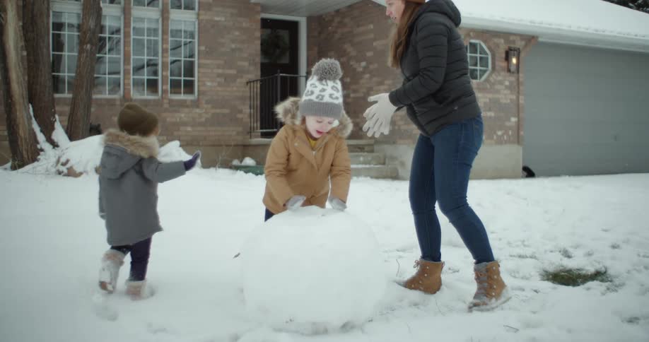 Mother and daughters build a snow man