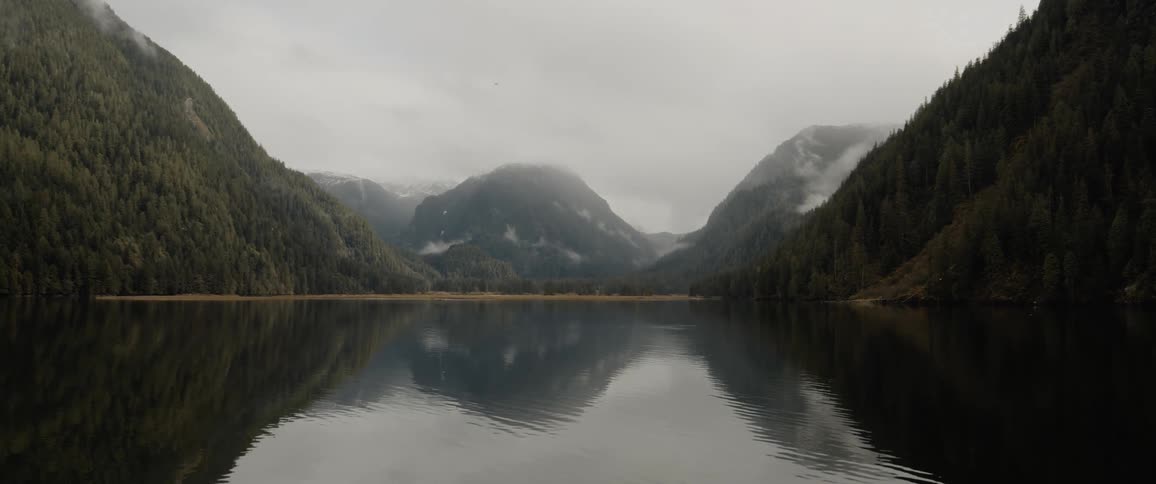 A canyon reflects onto clear lake water below