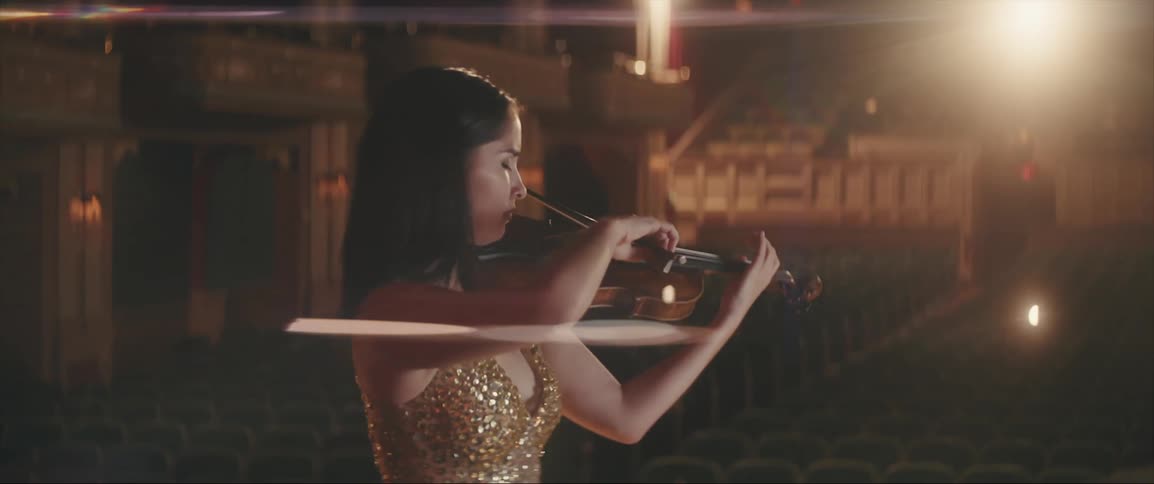 A woman is playing the violin in an empty auditorium