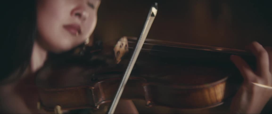 A woman is focused on her music as she plays a violin